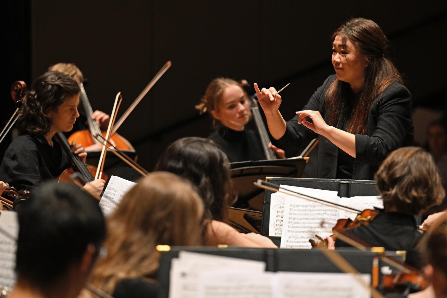 Orchestra Director Shou Ping Liu conducts the orchestra during a concert.