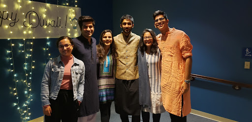 Six students pose together for a photo in front of fairy lights 