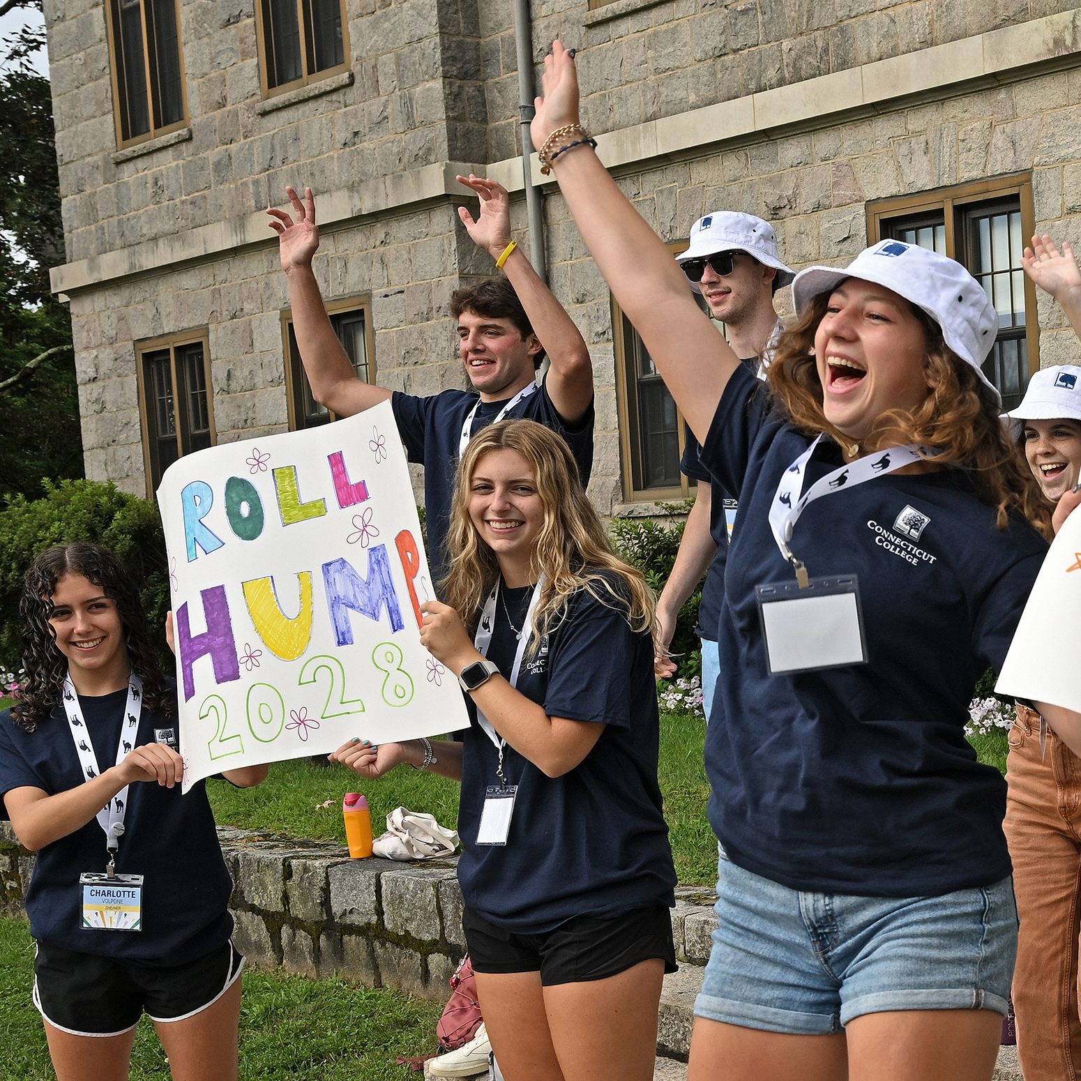 A group of students jump and cheer greeting newcomers to campus