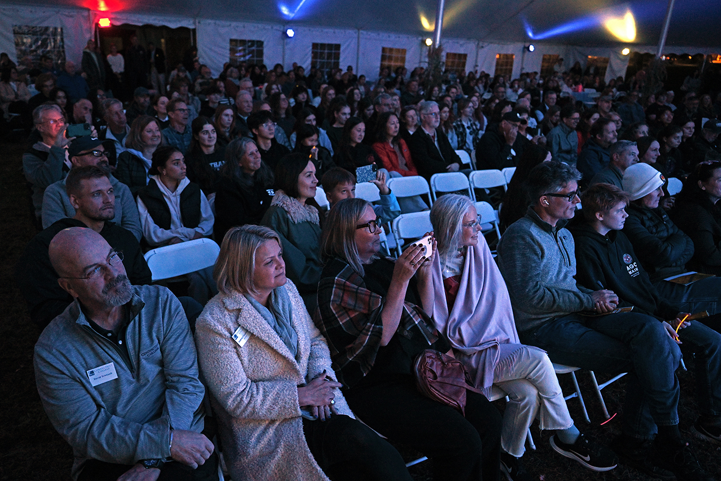 A large audience watches an a cappella concert under a big top tent.